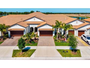 Stunning home exterior with a tile roof, multiple garages, a well-manicured lawn, and lush landscaping at 17576 Holly Well Ave, Wimauma, FL 33598