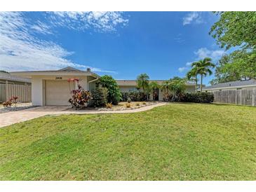 Charming single-story home with a lush green lawn, brick walkway, and mature landscaping, creating inviting curb appeal at 2908 Mayflower St, Sarasota, FL 34231