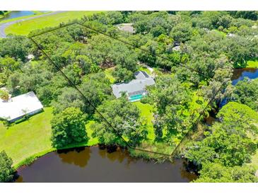 Expansive aerial view of wooded acreage, lake frontage, pool and mature trees define this private estate at 4576 Cooper Rd, Sarasota, FL 34232
