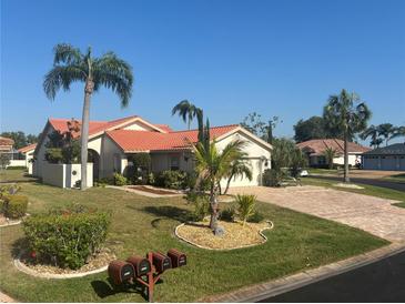 Charming single-story home features a red tile roof, lush landscaping, and a welcoming front lawn at 4907 Kilty E Ct, Bradenton, FL 34203