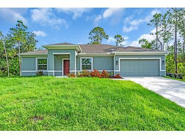 Charming single-story home with a well-manicured lawn, colorful flowers, and an attached two-car garage at 5672 Jonesboro Ave, North Port, FL 34288