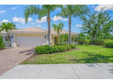 Charming home with lush landscaping, palm trees, a brick driveway, and a cream-colored exterior at 5821 Valente Pl, Sarasota, FL 34238