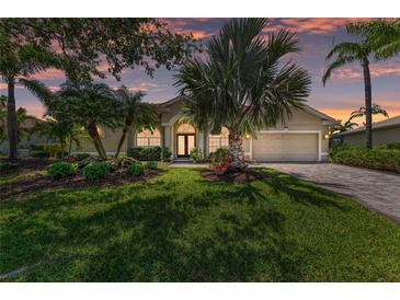 Charming single-story home with a well-manicured lawn, mature landscaping, and a brick-paved driveway at 7574 Camden Harbour Dr, Bradenton, FL 34212