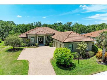 Charming home with a tile roof, lush landscaping, and a paved driveway at 9734 Carnoustie Pl, Bradenton, FL 34211