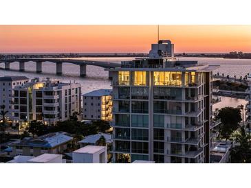 Luxury condo building with stunning views of the bay and a nearby bridge during sunset at 111 Golden Gate Pt # 802Ph, Sarasota, FL 34236