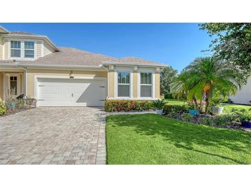 Charming home featuring manicured lawn, brick driveway, two-car garage and colorful flowers around the foundation at 11847 Meadowgate Pl, Lakewood Ranch, FL 34211