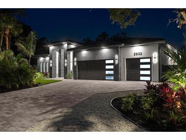 Stunning modern home with a two-car garage, lush landscaping, and elegant exterior lighting at night at 2632 Hawthorne St, Sarasota, FL 34239