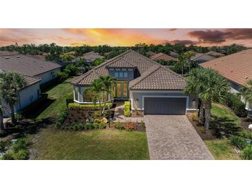 Beautiful home featuring a tile roof, landscaped yard, and a brick driveway leading to a two-car garage at 4908 Tivoli Run, Bradenton, FL 34211