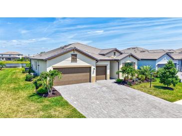 Beautifully landscaped home with a three-car garage and a paved driveway under a sunny blue sky at 4975 Seafoam Trl, Bradenton, FL 34211