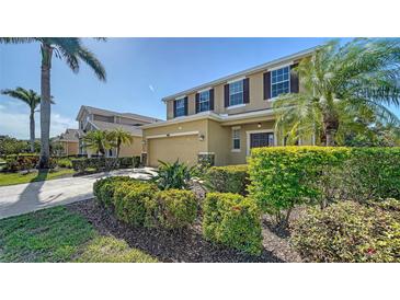 Two-story home with a tan exterior, dark shutters, well-manicured landscaping, and a two-car garage at 5403 Mang Pl, Sarasota, FL 34238