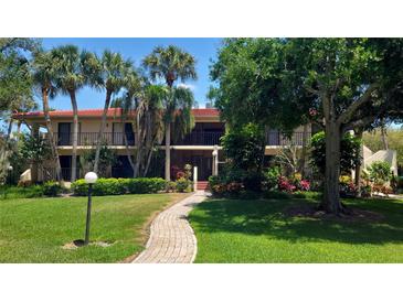 Charming condo building with lush landscaping, red roof, manicured lawn and a brick walkway at 6462 Wild Oak Bay Blvd # 245, Bradenton, FL 34210