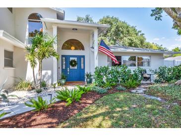 Charming home featuring a blue front door, decorative wreath, manicured landscaping, and an American flag at 2111 Ivory Pl, Sarasota, FL 34239