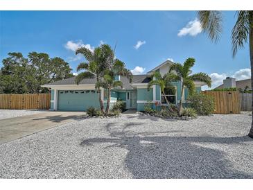 Charming turquoise home featuring a well-manicured lawn with tropical landscaping and a two-car garage at 6924 34Th W Ave, Bradenton, FL 34209