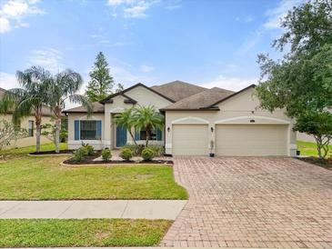 Charming single-story home featuring a manicured lawn, a three-car garage, and tropical landscaping at 2254 50Th Street E Cir, Palmetto, FL 34221