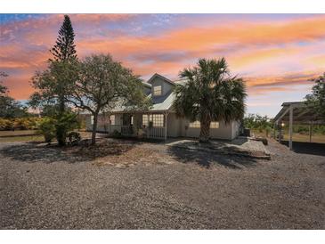 Charming home with a gravel driveway and beautiful landscaping at sunset at 28706 102Nd E Dr, Myakka City, FL 34251