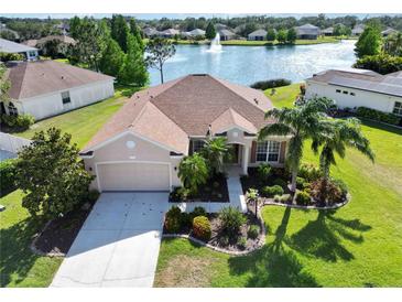 Beautiful single-story home features a well-manicured lawn, lush landscaping, and a scenic waterfront view with a fountain at 4262 70Th Street E Cir, Palmetto, FL 34221
