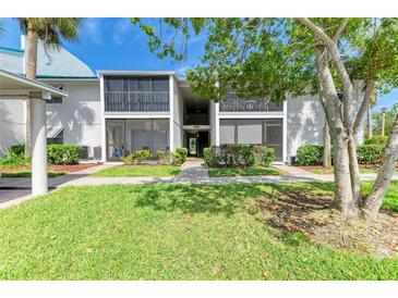 Inviting condo exterior with a well-maintained lawn and mature trees, offering a serene and peaceful setting at 5631 Midnight Pass Rd # 1007, Sarasota, FL 34242