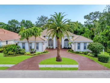 Stunning single-story home featuring a beautiful circular driveway and lush tropical landscaping at 6620 Saint James Xing, University Park, FL 34201