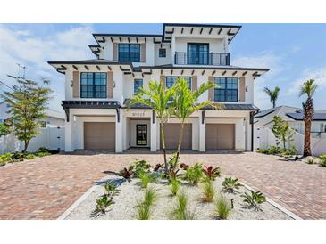 Stunning three-story home with a brick driveway, three car garage, and lush tropical landscaping at 723 S Blvd Of The Presidents, Sarasota, FL 34236