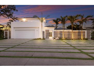 Stunning modern home featuring a well-manicured lawn, sleek design, and a beautiful sunset backdrop at 238 Island Cir, Sarasota, FL 34242
