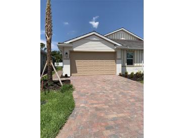 A charming home with a brick drive, tan garage door, and well maintained landscaping at 240 Ibiza Loop, Venice, FL 34292