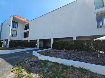 Bright condo building with stucco exterior, red roof, and well maintained landscaping in sunny weather at 3805 E Bay Dr # 302, Holmes Beach, FL 34217