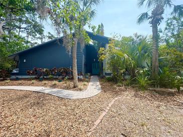 Landscaped front yard with brick walkway leading to a charming blue house with a teal front door at 5282 Box Turtle Cir, Sarasota, FL 34232
