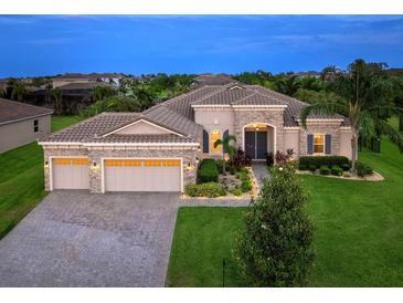 Beautiful single-story home featuring a three-car garage, manicured lawn, and a stone-accented facade at 603 165Th E St, Bradenton, FL 34212