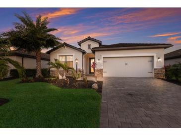 Charming single-Gathering home featuring a lush front yard, stone accents, and a two-car garage at 17418 Blue Ridge Pl, Lakewood Ranch, FL 34211