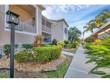 Beautiful condo exterior with lush landscaping, screened in porch, and walkway on a sunny day at 9560 High Gate Dr # 1622, Sarasota, FL 34238
