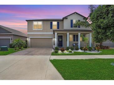 Charming two-story home with a well-manicured lawn and inviting front porch at 9646 Ivory Dr, Ruskin, FL 33573