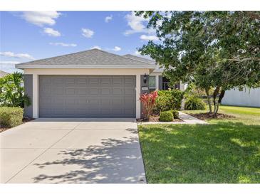 Charming single-story home featuring a gray garage door, landscaped front yard, and well-maintained lawn under a sunny sky at 9840 50Th Street E Cir, Parrish, FL 34219