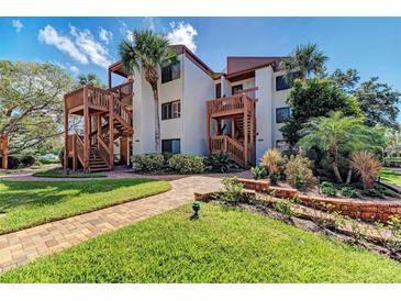 Inviting condo complex with tropical landscaping, wooden staircases, and a brick walkway to the charming building entrance at 1200 Cove Ii Pl # 832, Sarasota, FL 34242