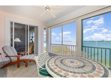Inviting sunroom features a decorative tile table and comfortable lounge chair with beautiful water views at 242 Hidden Bay Dr # 603, Osprey, FL 34229