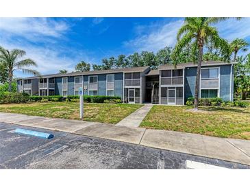 Condominium exterior with balconies, landscaping, and reserved parking under a blue sky at 5400 26Th W St # F104, Bradenton, FL 34207