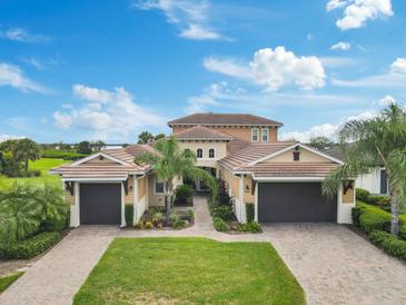 Stunning two-story home featuring a lush green lawn, beautiful landscaping, and a three-car garage at 5402 Tidewater Preserve Blvd, Bradenton, FL 34208
