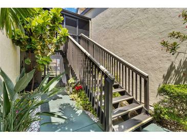 A view of the outdoor staircase leading to the upper level with mature foliage at 672 White Pine Tree Rd # 57, Venice, FL 34285