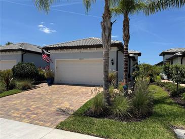 Charming single Gathering home with paved driveway and lush tropical landscaping and beautiful blue sky at 12291 Myrtle Bay Ct, Sarasota, FL 34238