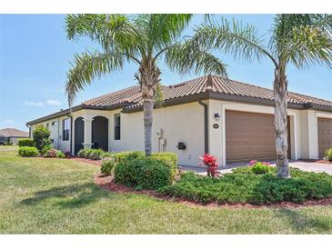 Charming home featuring a tile roof, two-car garage, and mature landscaping with palm trees at 12640 Felice Dr, Venice, FL 34293