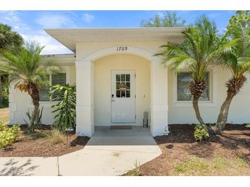 Inviting front entrance with arched doorway and tropical landscaping at 1709 Kerman St, North Port, FL 34288