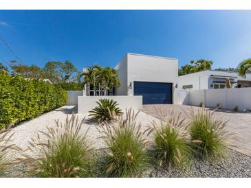Charming single-Gathering home featuring a blue garage door, pristine white facade, and decorative landscaping at 2365 Novus St, Sarasota, FL 34237
