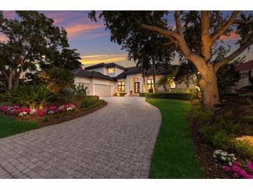 Beautiful home exterior with a paved driveway and lush landscaping and manicured lawn at 3302 Sabal Cove Ln, Longboat Key, FL 34228