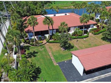 Beautiful condo has a red tile roof and lush landscaping, near a golf course and a pond at 3500 El Conquistador Pkwy # 301, Bradenton, FL 34210
