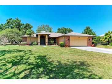 Charming single-story home featuring a well-manicured lawn, mature trees, and an attached two-car garage at 410 136Th E Ct, Bradenton, FL 34212