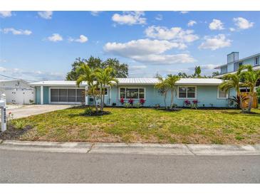 Charming one-story home with a blue exterior, well-manicured lawn, and lovely tropical landscaping and palm trees at 4309 Pinfish Ln, Palmetto, FL 34221