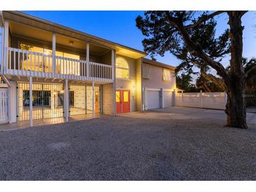 Two-story coastal home with covered balconies, three-car garage, ample parking and a red front door at 501 Key Royale Dr, Holmes Beach, FL 34217