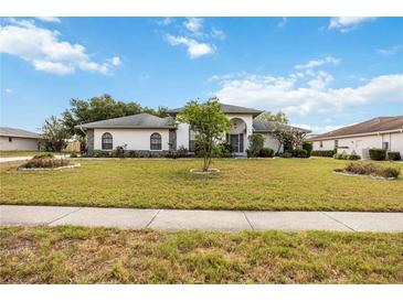 Charming one-story home with a well-manicured lawn and lush landscaping under a sunny blue sky at 6405 99Th E St, Bradenton, FL 34202