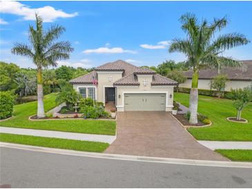 Charming single-story home featuring lush landscaping, a brick driveway, and two palm trees in the front yard at 9774 Highland Park Pl, Palmetto, FL 34221