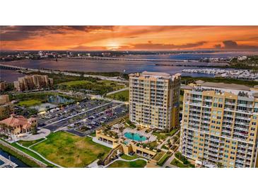 Stunning sunset view of luxury high-rise condos with a pool, lush landscaping, and ample parking near the bay and city at 130 Riviera Dunes Way # 502, Palmetto, FL 34221