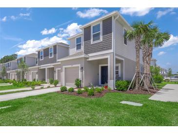Charming two-story townhome featuring a well-manicured lawn, landscaping, and a one-car garage at 15051 Ginetti St, Nokomis, FL 34275